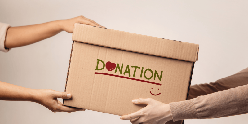 Image of cardboard box handed from one person to another. Text on box reads Donation