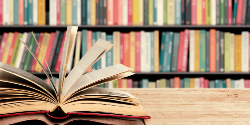 Shelf of books and an open book on a table