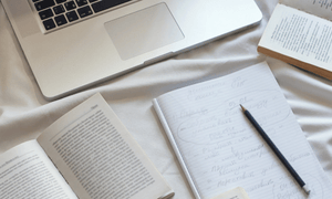 Image of notebook, pencil, open books and laptop.