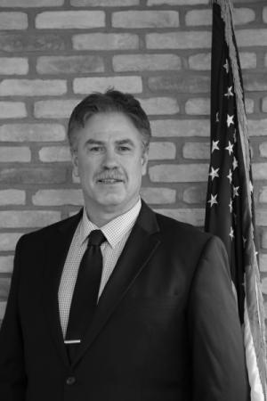 Black and White Photo of Mayor Gabriel in a suit in front of the American flag.
